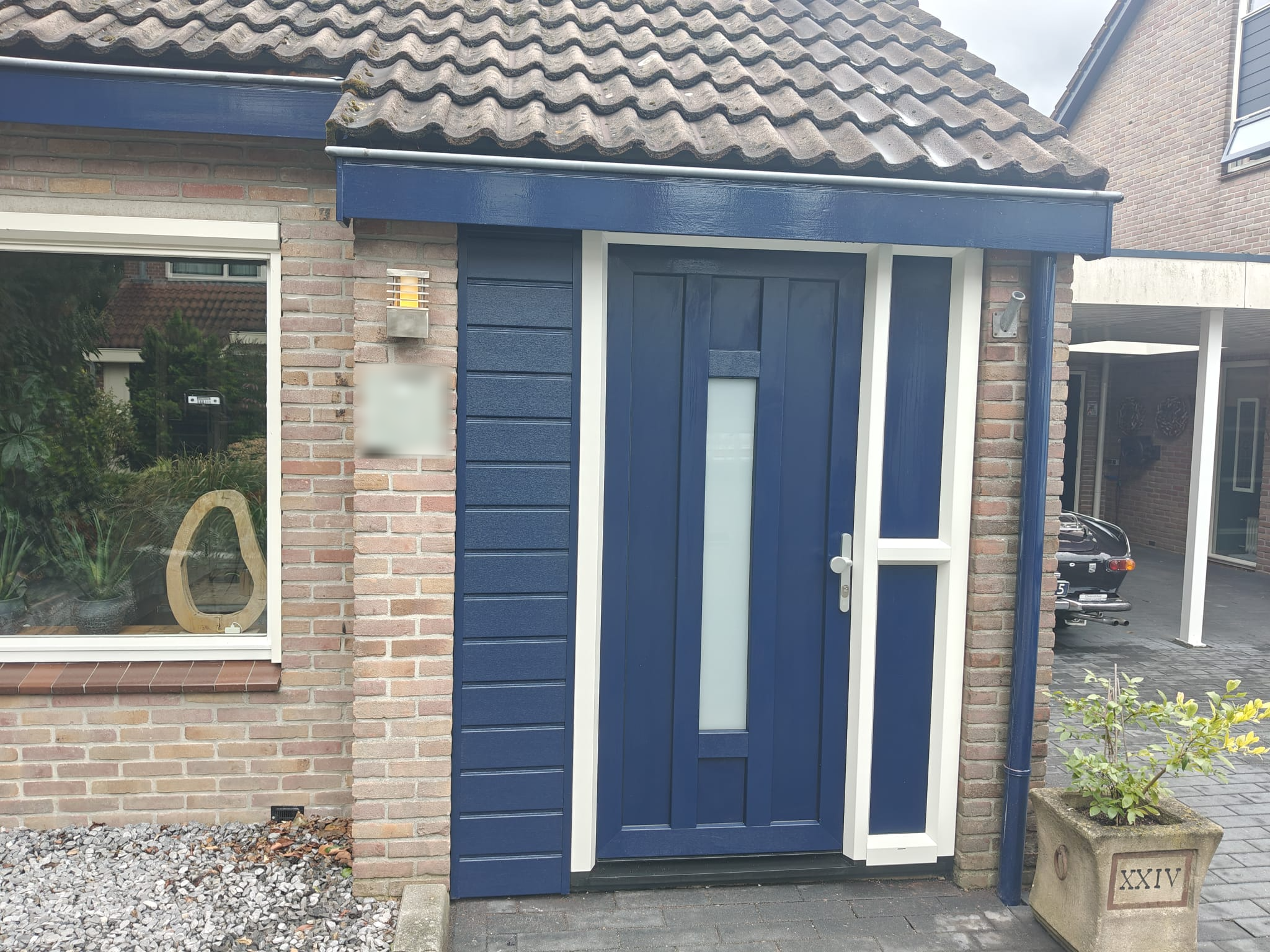 Blauwe kunststof voordeur met zijlicht en bijpassende gevelbekleding